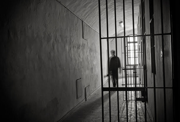 photo illustration: inmate in greyscale cell (iStockphoto)