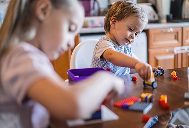 Kids playing with colourful bricks at dining table