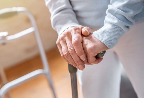 Close up of senior woman's hands holding walking stick (stock photo)
