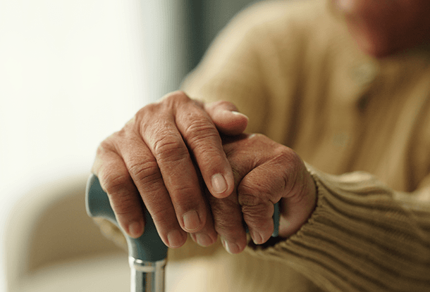 photo: hands of a seated elderly person holding a cane (iStockphoto)